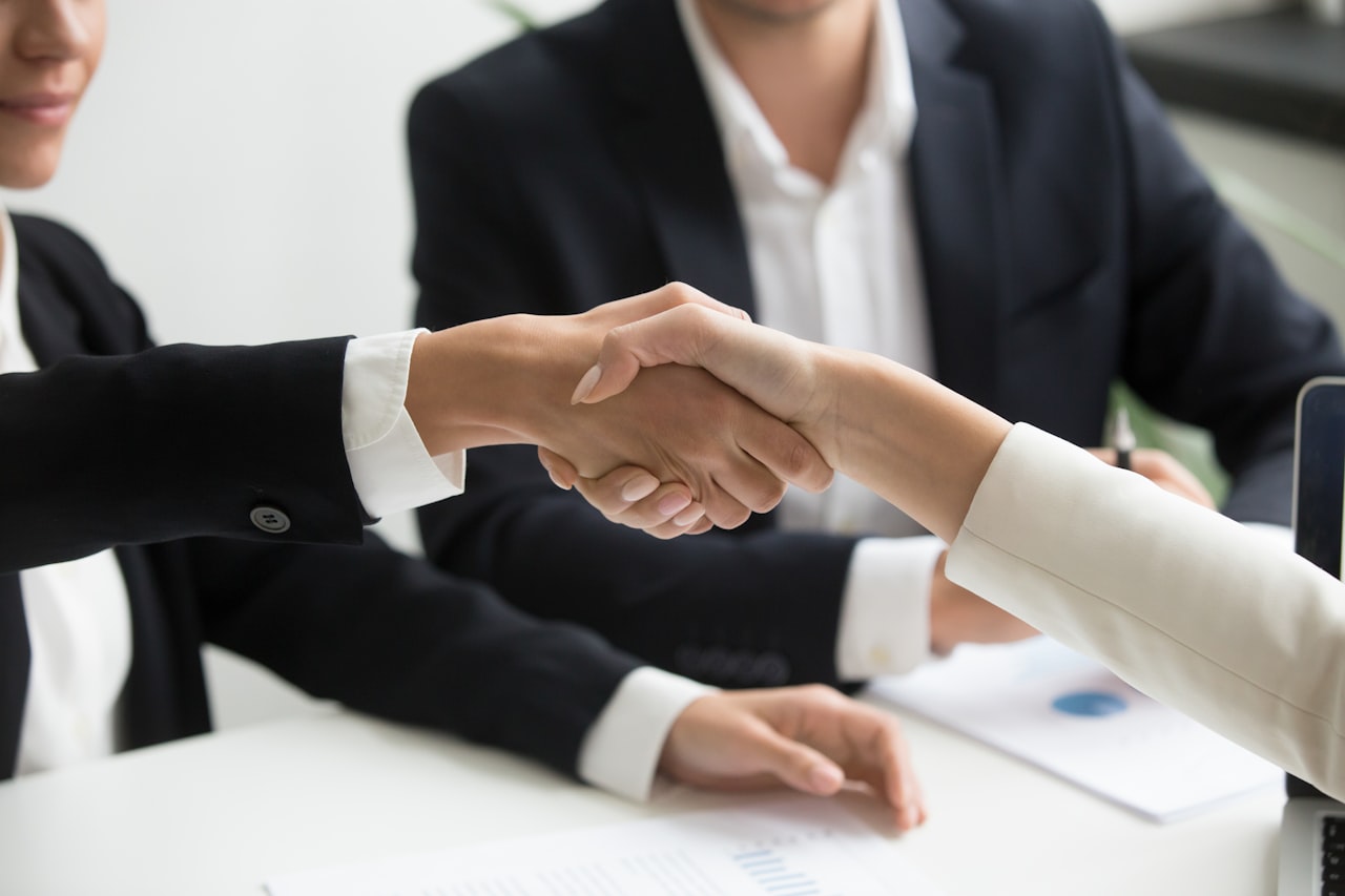 Business handshake over a laptop in a meeting